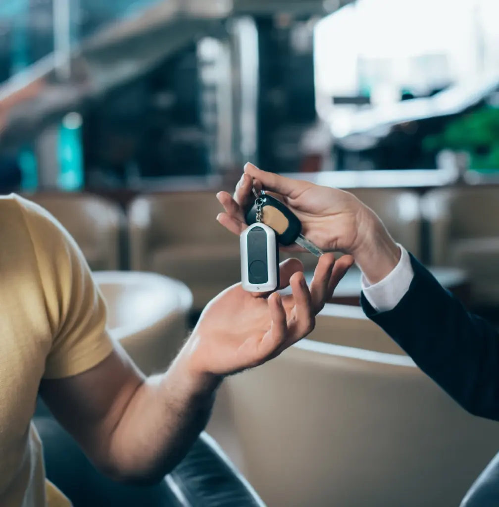 Jemand überreicht einem Kundem die Autoschlüssel, was einen erfolgreichen Abschluss des Verkaufs symbolisiert.